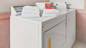 A front-loading washing machine with a Tide detergent box on top. - Sapphire Inn & Suites- Deer Park (Deer Park)