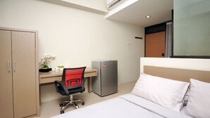 Une chambre d’hôtel comprenant un lit, un bureau avec une chaise, un réfrigérateur et une armoire.