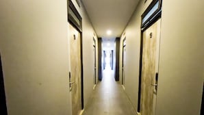 A long, narrow hotel hallway with doors on both sides, leading to individual rooms.