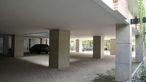 A covered parking area with concrete pillars, a paved floor, and a car parked inside.