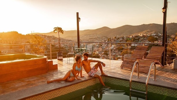 Ein Poolbereich mit Blick auf eine Skyline und Hügel im Hintergrund.