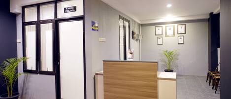 A reception area with a wooden reception desk, a potted plant, and framed certificates on the wall.