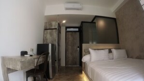 A modern hotel room with a bed, a desk, and a chair. - Dparagon Gajah Mada (Jakarta)