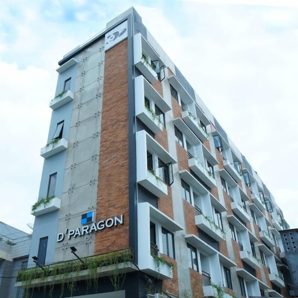 A multi-story building with a modern design, featuring a mix of brick and concrete facades, and balconies with greenery.