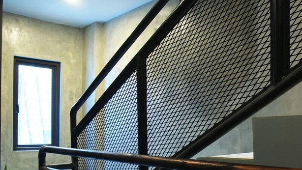 A staircase with metal railings and a mesh panel, leading to an upper floor. - Dparagon Gajah Mada (Jakarta)
