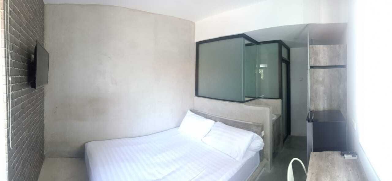 Een moderne hotelkamer met een bed, een aan de muur bevestigde televisie en een douchecabine van glas.