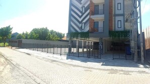 A modern multi-story building with a zigzag facade pattern, a gated entrance, and a paved driveway. - Djuragan Kamar Gunung Anyar (Surabaya)