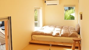 Une chambre à coucher au style minimaliste, avec un lit, une petite table et un tabouret.