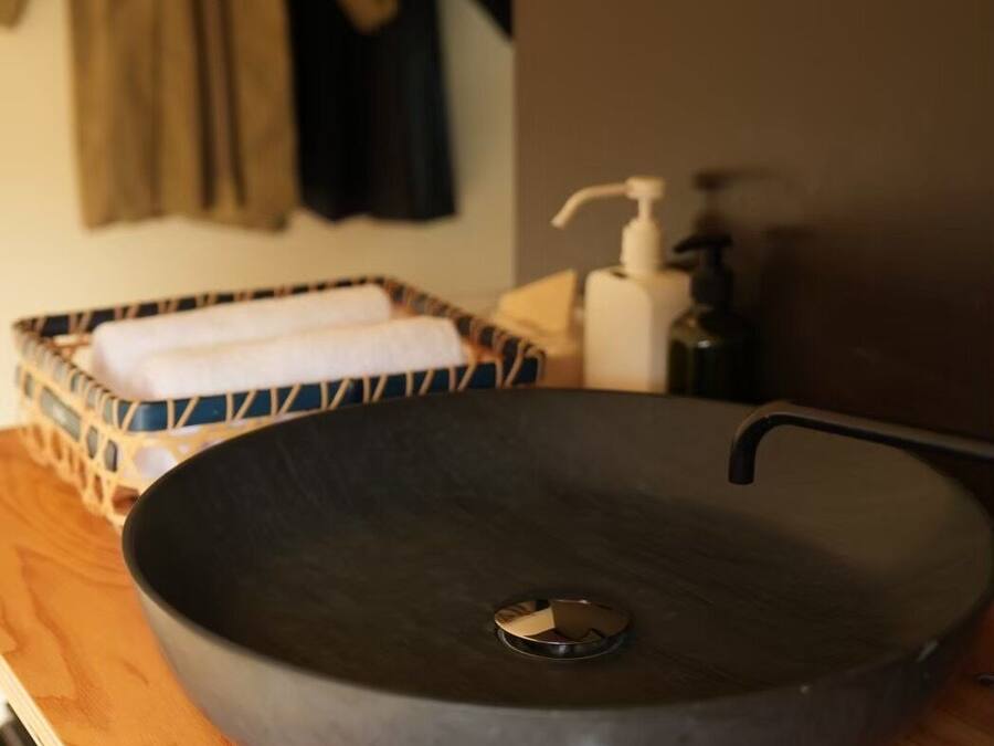 A round black sink with a faucet on a wooden countertop.