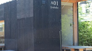 Un bâtiment moderne à l’extérieur en bois foncé, portant l’inscription « A01 Jyubako ».