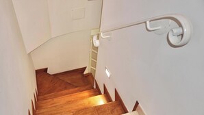 A wooden staircase with a handrail and a light switch on the wall.