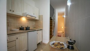 A compact kitchen with white cabinets, a built-in oven, and a coffee maker on the counter.