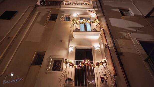A building facade with multiple balconies adorned with festive lights and garlands.