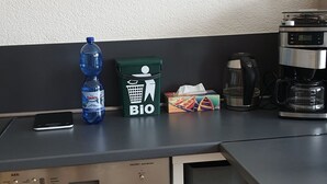 Een kitchenette met een vaatwasser, een koffiezetapparaat, een waterfles en zakdoekjes.