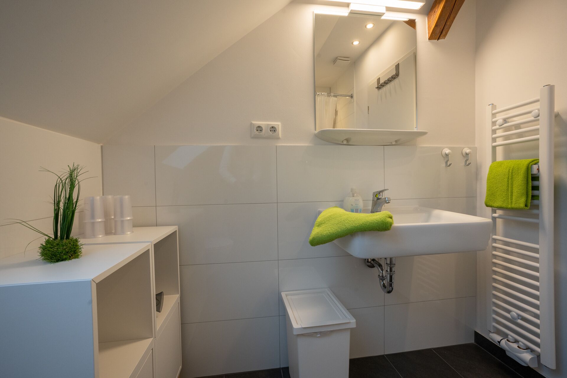 Un baño moderno con lavamanos, espejo y toallero blancos.
