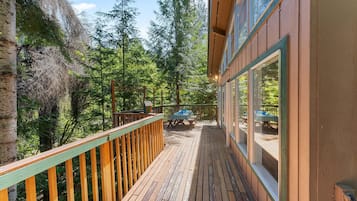 Une terrasse en bois dotée d’une rambarde, qui offre une vue sur une zone boisée.