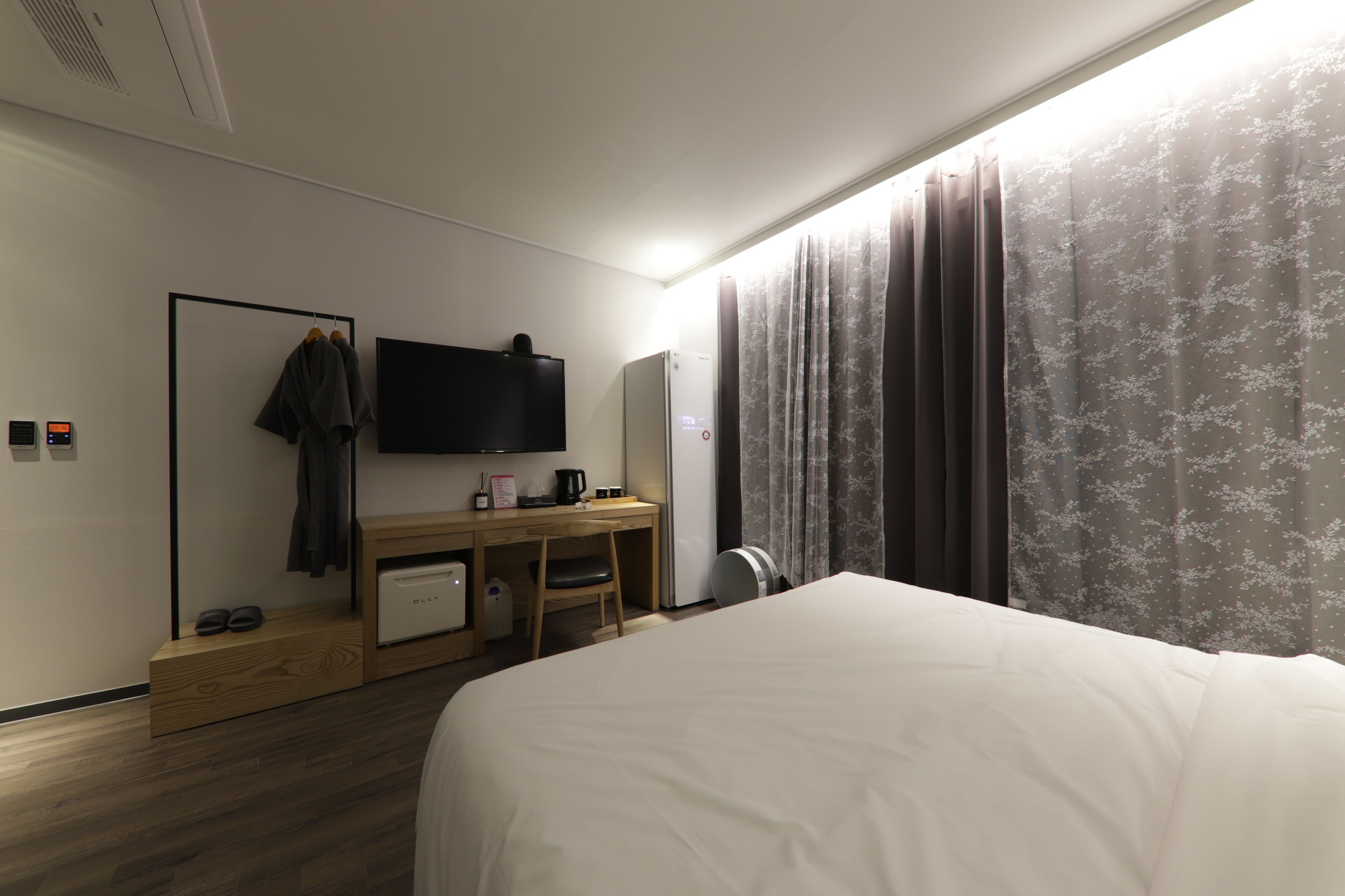 Ein modernes Hotelzimmer mit einem großen Bett, einem Schreibtisch, einem Flachbildfernseher, einer Kaffeemaschine und einem Kleiderschrank.