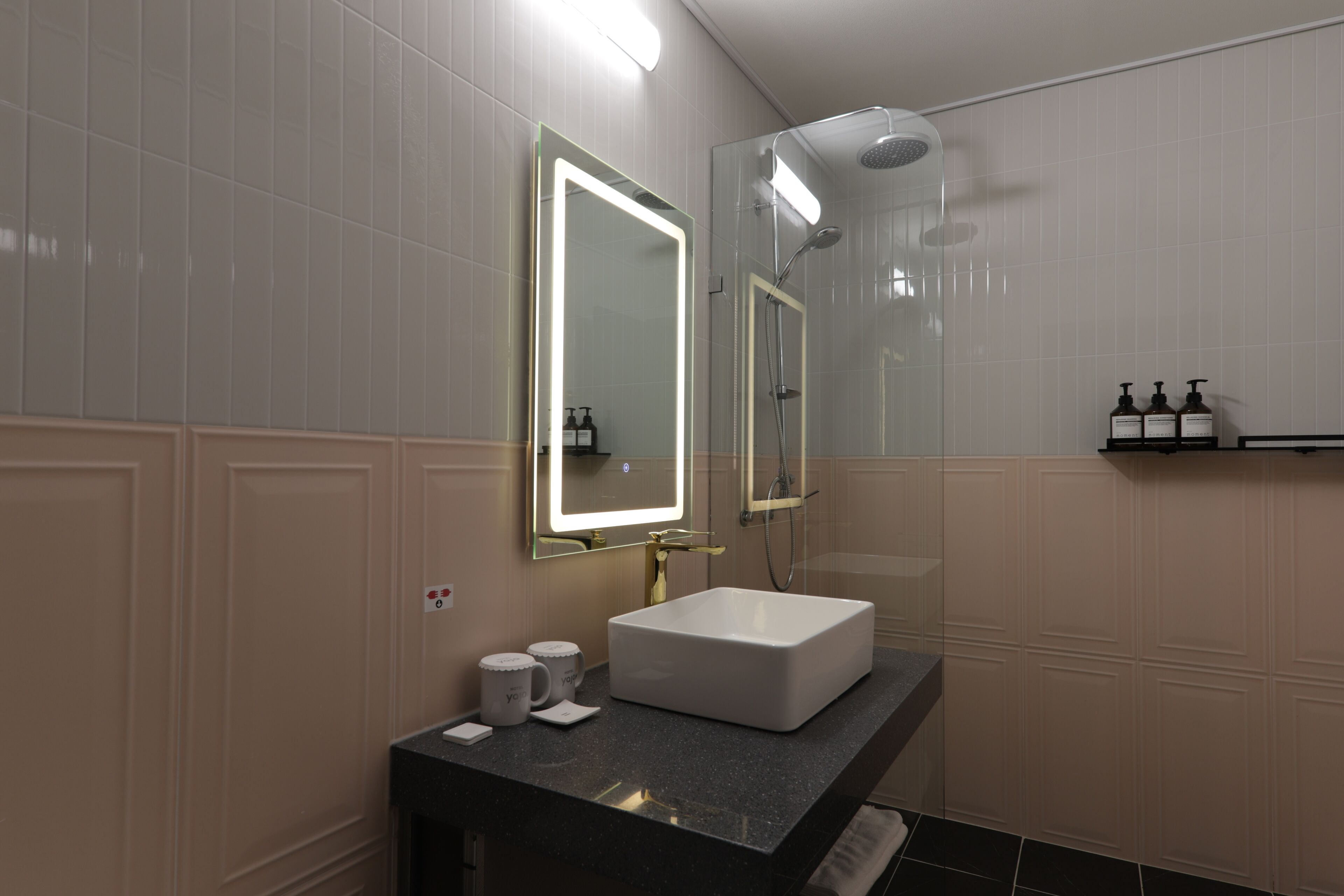 A modern bathroom with a large mirror, a white sink, and a shower area.