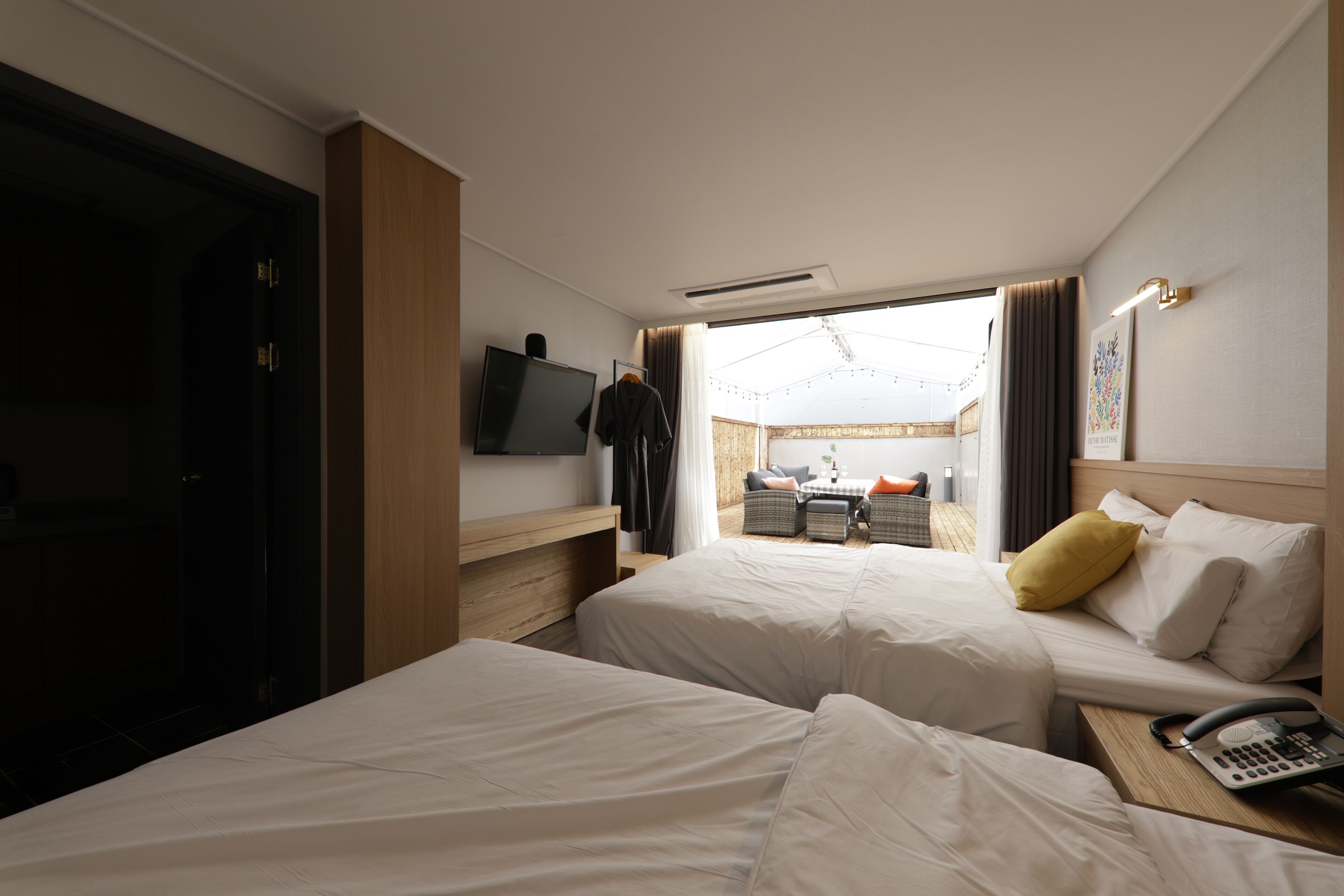 Habitación de hotel con dos camas, televisión, escritorio con teléfono y vista al área exterior.