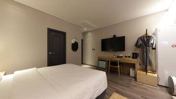 Una camera d'albergo con un letto, una scrivania, una televisione e un armadio.