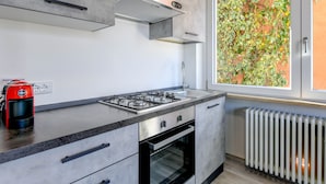 Cocina moderna con estufa a gas, horno y ventana con vista a una enredadera verde.