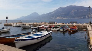 Un port de plaisance où sont amarrés différents types de bateaux, une côte rocheuse et une montagne en arrière-plan.