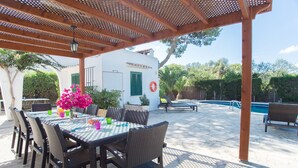 An outdoor patio with a table and chairs, a pool, and a covered area with a pergola. - Spacious holiday home Dos Pinos with pool, A/C 24h, Wi-Fi, near Cala Esmeralda (Santanyí)