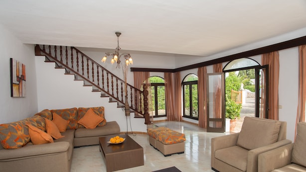 A spacious living room with a wooden staircase, a large sofa, a coffee table, and a comfortable armchair. - Spacious holiday home Dos Pinos with pool, A/C 24h, Wi-Fi, near Cala Esmeralda (Santanyí)