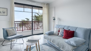 A modern living room with a balcony, a sofa, a chair, and a small table. - 50m from the beach, seaview flat for 2 (Pléneuf-Val-André)