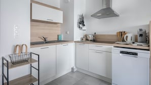 A modern kitchen with white cabinets, a stainless steel range hood, a coffee maker, and a toaster. - 50m from the beach, seaview flat for 2 (Pléneuf-Val-André)