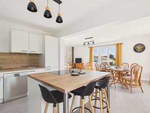 A modern kitchen with white cabinets, a wooden island, and black chairs. - Holiday home for 6 in Saint Hilaire de Riez (Saint-Hilaire-de-Riez)