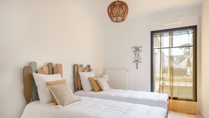 Un dormitorio con dos camas, un ventanal con vistas y una lámpara colgante.