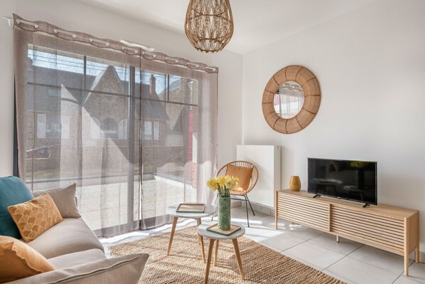 Een moderne woonkamer met een bank, televisie en decoratieve elementen.