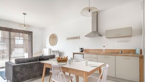 Eine moderne Küche mit Essbereich, ausgestattet mit einem weißen Tisch, Holzstühlen und einem Einbauofen.