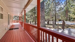 A covered porch with red railings, a wooden floor, and a view of a snowy landscape with trees. - Cascade Cabin Mountain Getaway with Private Beach (Cascade)