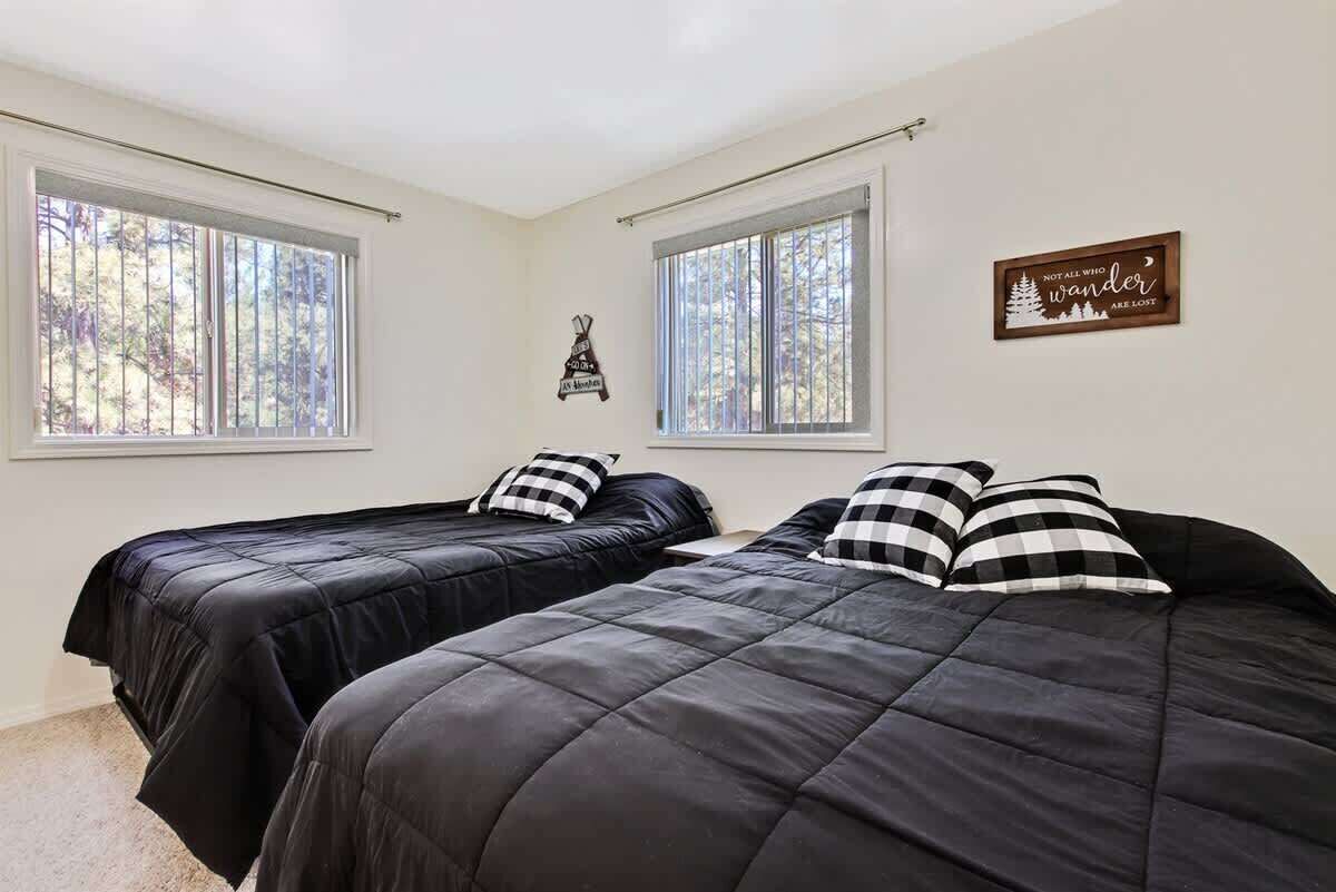 A bedroom with two beds, a window, and a wall decoration.