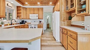 A kitchen with wooden cabinets, a central island, a microwave, and a refrigerator. - Cascade Cabin Mountain Getaway with Private Beach (Cascade)