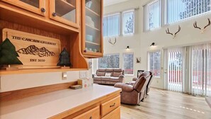 A spacious living area with a wooden cabinet, a fireplace, a sofa, and a dining table. - Cascade Cabin Mountain Getaway with Private Beach (Cascade)