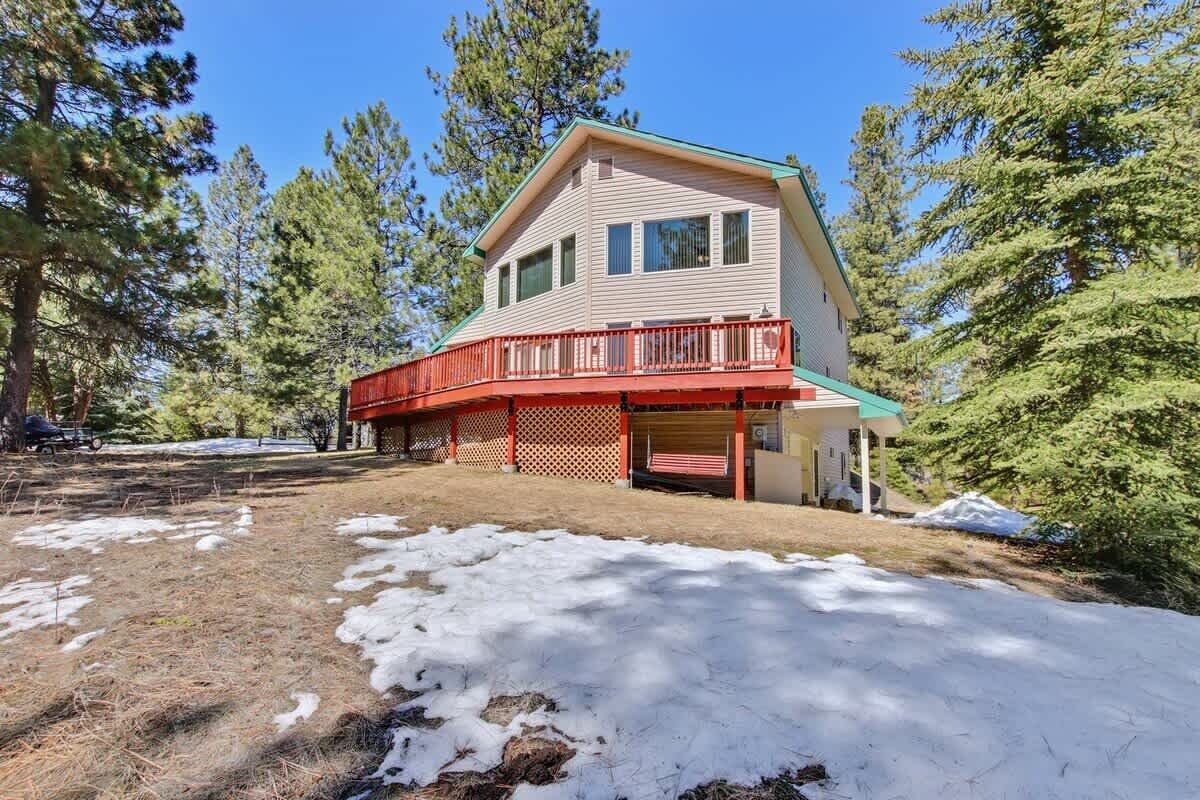 A two-story house with a red balcony, surrounded by trees.