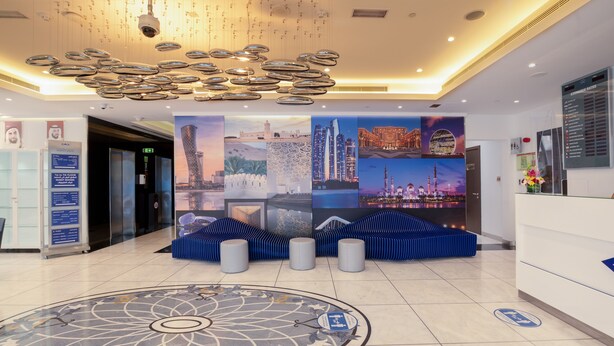 A modern hotel lobby with a central seating area, a large decorative ceiling, and a floor with a geometric pattern. - Gravity Hotel (Abu Dhabi)