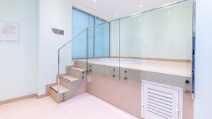 A modern bathroom with a glass-enclosed shower, a beige-tiled floor, and a white ceiling with recessed lighting. - Gravity Hotel (Abu Dhabi)