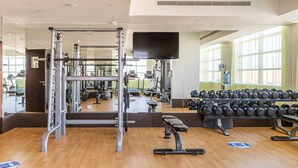 A gym with exercise equipment, a television, and a mirror. - Gravity Hotel (Abu Dhabi)