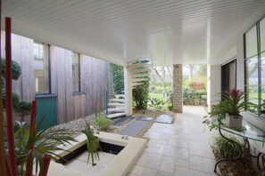 Eine moderne Außenpatio mit Wendeltreppe, Steinpfeilern und Kübelpflanzen.