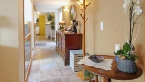 A hallway with a wooden table and chairs, a mirror, and a plant. - 4-star house with patio and garden (Arradon)