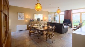 A spacious living room with a dining area, a fireplace, and a large window offering a view of the outdoors. - 4-star house with patio and garden (Arradon)