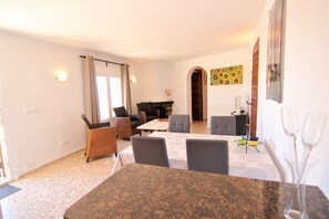 Relax in a spacious living area with a sofa, chairs, and a coffee table, surrounded by artwork and comfortable seating options.