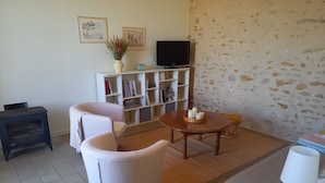 Een woonkamer met een bank, een houten tafel, een televisie en een boekenkast.