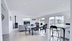 A modern kitchen with a dining area, large windows, and a built-in stove. - Les Thoniers - Etel - Gîte (ETEL)