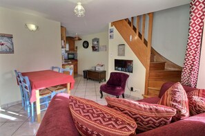 Un salon avec un canapé, une table à manger et une cuisine à l’arrière-plan.