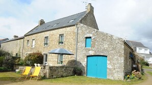 A stone building with a blue door, a small garden, and two yellow chairs. - Les Saules Blancs - Plouharnel (PLOUHARNEL)